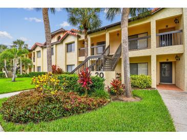 Inviting condo exterior with lush landscaping and palm trees offers a tranquil residential setting at 1801 E Lake Rd # 20 G, Palm Harbor, FL 34685