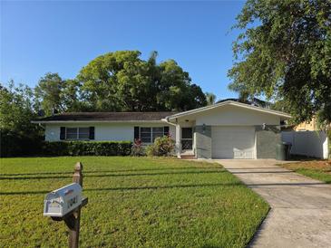 Charming single-story home with a well-maintained lawn and lush greenery at 2045 Summit Dr, Dunedin, FL 34698