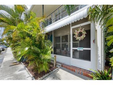 Charming entrance with screen door, awning, and lush tropical landscaping provides a welcoming feel to this beautiful condo at 4154 56Th N St # 720, Kenneth City, FL 33709