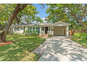 Charming single story home featuring a well maintained lawn, lush trees, and a private carport at 4309 W Empedrado St, Tampa, FL 33629