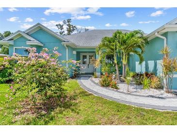 Charming blue single-story home featuring a paved walkway and lush landscaping with palm trees at 716 Laurel Ave, Venice, FL 34285