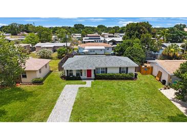 Charming single-story home featuring a red front door, green lawn, and meticulously manicured landscaping at 8339 75Th Ave, Seminole, FL 33777