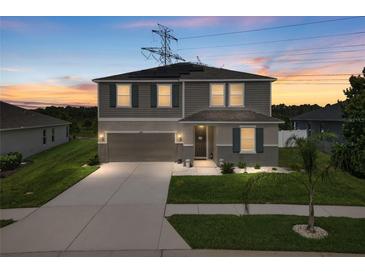 Charming two-story home featuring gray siding, green shutters, manicured lawn and a spacious driveway, perfect for families at 12481 Aston Dr, Hudson, FL 34669