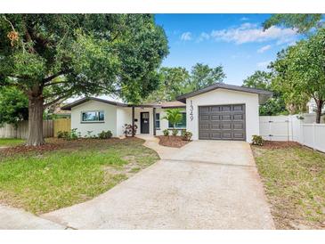Charming single story home with a well-manicured lawn, mature trees, and a driveway leading to the garage at 1349 Tyrone N Blvd, St Petersburg, FL 33710