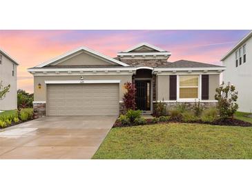 Charming single-story home with a two-car garage, stone accents, and well-maintained landscaping at 5620 Night Owl Ter, Palmetto, FL 34221