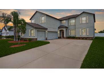 Two-story home features an attached two-car garage, a well-manicured lawn, and professional landscaping at 13913 Felix Will Rd, Riverview, FL 33579
