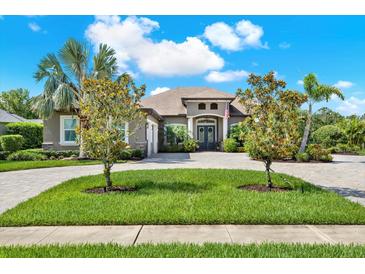 Charming single-story home featuring lush landscaping, a paver driveway, and a welcoming double-door entrance at 15415 Mulholland Rd, Parrish, FL 34219