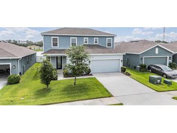 Two-story home features a light-blue facade, a two-car garage, and a well-manicured lawn at 8576 Broadstone Dr, Wesley Chapel, FL 33544