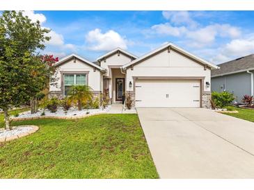 Beautiful single-story home with a manicured lawn, white rock garden, and neutral color palette at 944 Old Windsor Way, Spring Hill, FL 34609