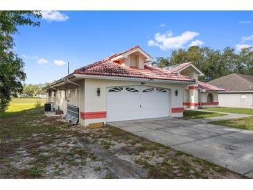 Home exterior featuring an attached garage and a red tile roof in a sunny setting at 10446 Baylor Dr, Spring Hill, FL 34608