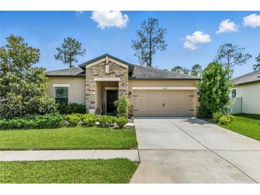 Charming single-story home featuring a stone facade, well-manicured lawn, and a two-car garage at 18596 Rococo Rd, Spring Hill, FL 34610