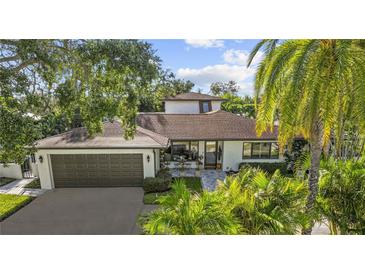 Charming home showcasing lush landscaping, a gray roof, and an attached two-car garage at 208 Live Oak Ln, Largo, FL 33770