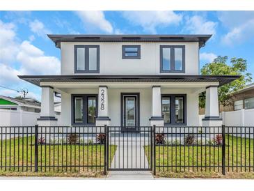 Charming two-story home features modern black and white color scheme, front yard landscaping and a black metal fence at 2328 W La Salle St, Tampa, FL 33607