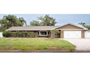 Charming single-story home featuring a brick and vinyl facade with a two-car garage and manicured landscaping at 3235 Walnut Ne St, St Petersburg, FL 33704
