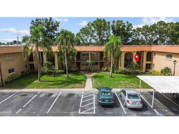 Condo exterior featuring a well-maintained lawn, palm trees, and convenient covered parking at 4500 E Bay Dr # 106, Clearwater, FL 33764
