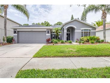Charming single-story home featuring a well-manicured lawn, palm trees, and a two-car garage at 8814 N River Rd, Tampa, FL 33635