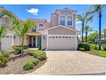 Charming two-story home featuring a two-car garage, tropical landscaping, and a welcoming blue front door at 1411 Tessano Pl, Palm Harbor, FL 34683