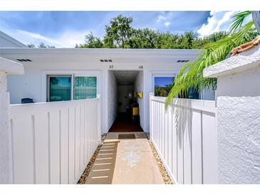 Inviting condo exterior with white fence, walkway, and lush tropical landscaping at 1655 S Highland Ave # B118, Clearwater, FL 33756