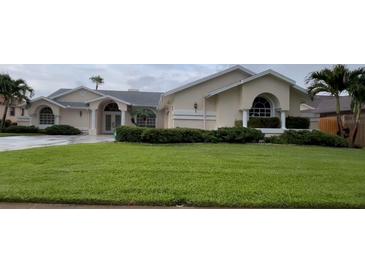 Charming single-story home with a well-manicured lawn, lush landscaping, and a circular driveway at 2635 Jarvis Cir, Palm Harbor, FL 34683
