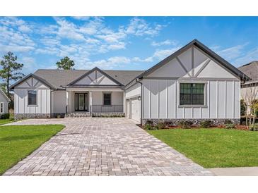 Stunning single-story home featuring a brick driveway, gray accents, and professionally landscaped front yard at 4799 Hickory Oak Loop, Brooksville, FL 34601