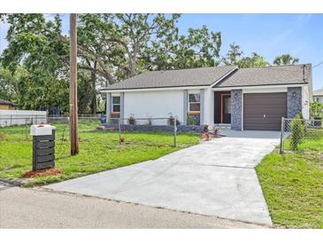 Charming single-story home featuring a well-manicured lawn, driveway, and stone accents at 9511 N Hyaleah Rd, Tampa, FL 33617