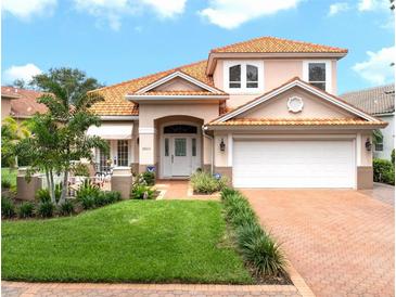 Charming two-story home featuring a red tile roof, manicured lawn, and a welcoming front patio at 9800 Sago Point Dr, Seminole, FL 33777