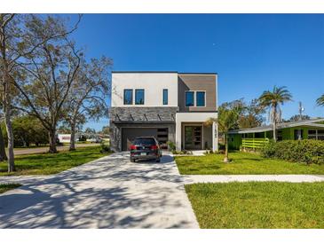 Modern two-story home with a well-manicured lawn, concrete driveway, and a black SUV parked in front at 1625 55Th S St, Gulfport, FL 33707