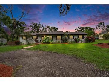 Charming single-story home with white brick, manicured lawn, and lush landscaping with a stone walkway at 8222 Valrie Ln, Riverview, FL 33569
