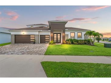 Stunning two-story home featuring a three-car garage, paver driveway, and beautifully manicured lawn at 8752 Loft Pt, Wesley Chapel, FL 33545