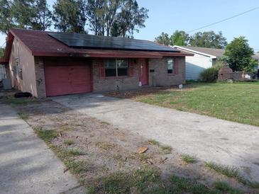 Charming single-story brick home featuring a driveway and solar panels on the roof at 902 Marshall St, Clearwater, FL 33755