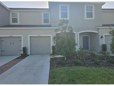 Inviting townhome showcasing a manicured lawn, gray exterior, and a convenient attached garage at 10573 Oakside Dr, Palmetto, FL 34221