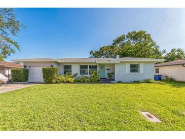 Charming single-story home features a well-manicured lawn, tidy landscaping, and a welcoming, light-blue front door at 1220 Magnolia Dr, Clearwater, FL 33756