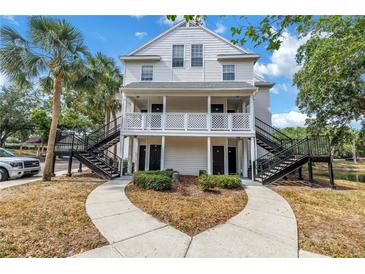 Two-story condo building featuring black stairs, white siding, and tidy landscaping, showcasing curb appeal at 3300 Haviland Ct # 103, Palm Harbor, FL 34684