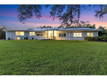 Stunning home exterior at twilight with a large front lawn and solar panels at 3425 W Forest Lake Cir, Sarasota, FL 34232