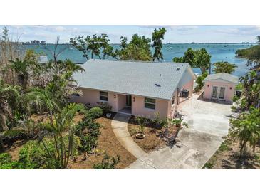 Charming waterfront home with lush landscaping, a concrete driveway, and a detached garage at 4749 Baywood Point S Dr, Gulfport, FL 33711