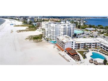 Stunning aerial view showcasing the beachfront condo, pristine beach, and sparkling pools at 4950 Gulf Blvd # 404, St Pete Beach, FL 33706