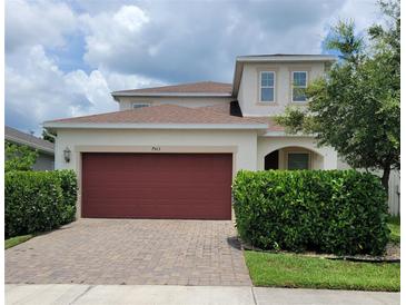 Two-story home featuring a brick driveway, well-maintained landscaping and a red two-car garage door at 7563 Ashcroft Dr, Wesley Chapel, FL 33545