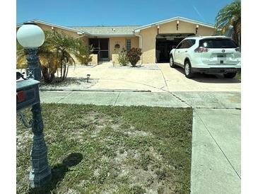 A charming single story home, features a two car garage, landscaping, and a well-maintained lawn at 2043 Sugarbush Dr, Holiday, FL 34690