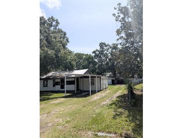 Modest home with covered porch and large trees creating a shaded yard at 2414 S 67Th St, Tampa, FL 33619