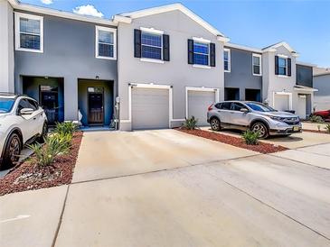 An exterior of townhomes featuring attached garages and modern design elements at 32977 Kaloko Rd, Wesley Chapel, FL 33543
