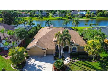 Stunning waterfront home featuring a tile roof, two-car garage, lush landscaping, and palm trees at 3895 Mimosa Pl, Palm Harbor, FL 34685
