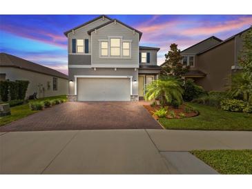 Charming two-story home with landscaped yard, brick driveway, two-car garage, and neutral gray paint at 4077 Cadence Loop, Land O Lakes, FL 34638