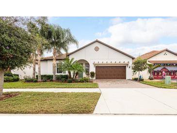 Charming single-story home with a two-car garage, and a well-manicured lawn with tropical landscaping at 16831 Banner Shell Pl, Wimauma, FL 33598