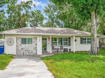 Charming single-story home with a well-maintained lawn, covered porch and an inviting outdoor seating area at 2160 Ne Coachman Rd, Clearwater, FL 33765