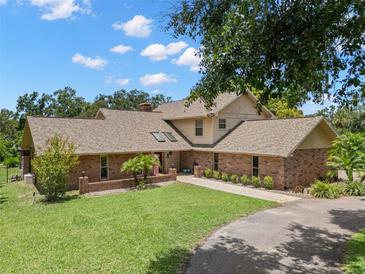 Charming brick home with a well-manicured lawn, complemented by mature trees and landscaping at 2306 S Valrico Rd, Valrico, FL 33596