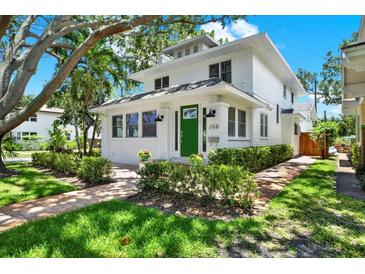 Charming two-story home featuring a green door, manicured landscaping, and brick pathway at 258 14Th Ne Ave, St Petersburg, FL 33701