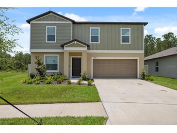 Charming two-story home features a two-car garage and a well-manicured lawn with tasteful landscaping at 34797 Rainville Loop, Zephyrhills, FL 33541