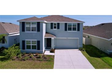 Charming two-story home with gray siding, dark shutters, well-maintained landscaping, and an attached two-car garage at 5470 Flint Hills Dr, Wimauma, FL 33598