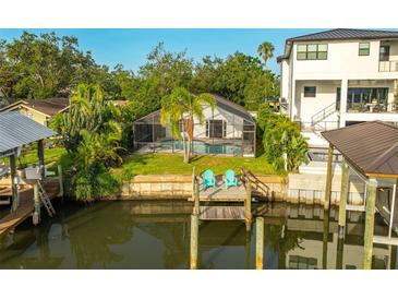 Relaxing backyard oasis with screened-in pool, lush landscaping, and private dock on the water at 593 Marmora Ave, Tampa, FL 33606