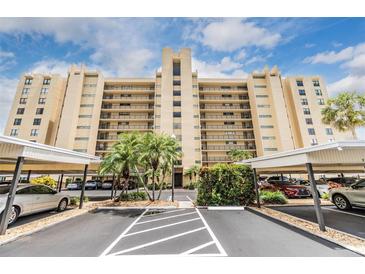 Multi-story condo building featuring balconies, palm trees, and covered parking at 2621 Cove Cay Dr # 302, Clearwater, FL 33760